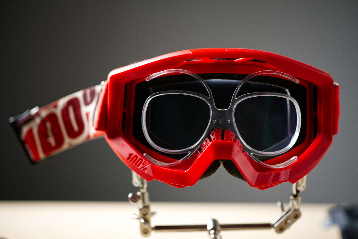 Red 100% MX goggle on display stand showing prescription insert mini glasses frame inside