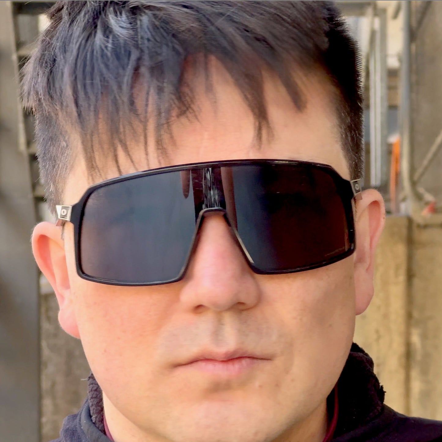 Person wearing Oakley Sutro with prescription insert, black frame and dark lenses