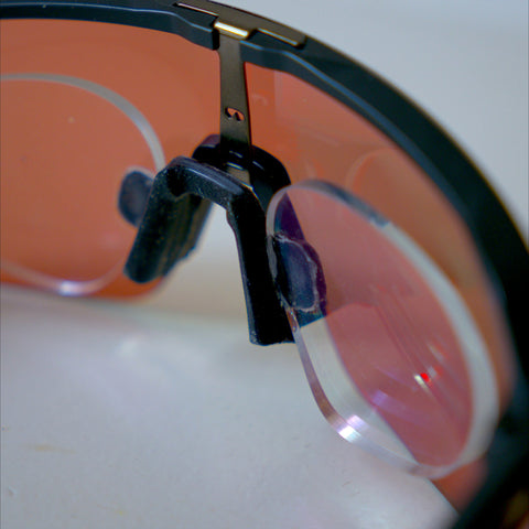 Close-up of Oakley Sutro Lite prescription insert nosepiece clip, red Prizm Road lens
