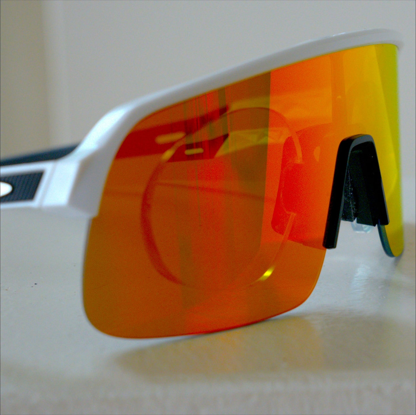 Side angle view of Oakley Sutro Lite S, white frame with orange Prizm lens, prescription insert visible