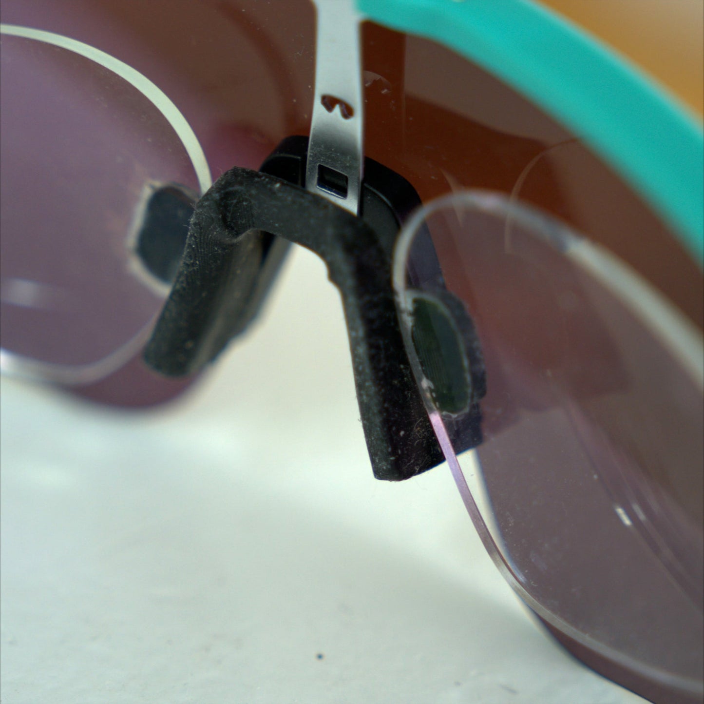 Close-up of Oakley Sutro Lite Sweep prescription insert nosepiece clip, teal frame