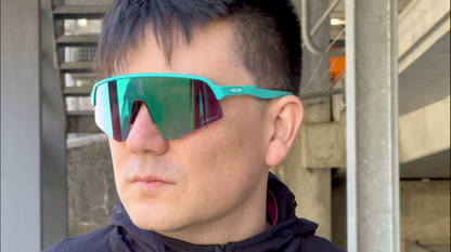 Person wearing teal Oakley Sutro Lite Sweep with prescription insert and green mirrored lens