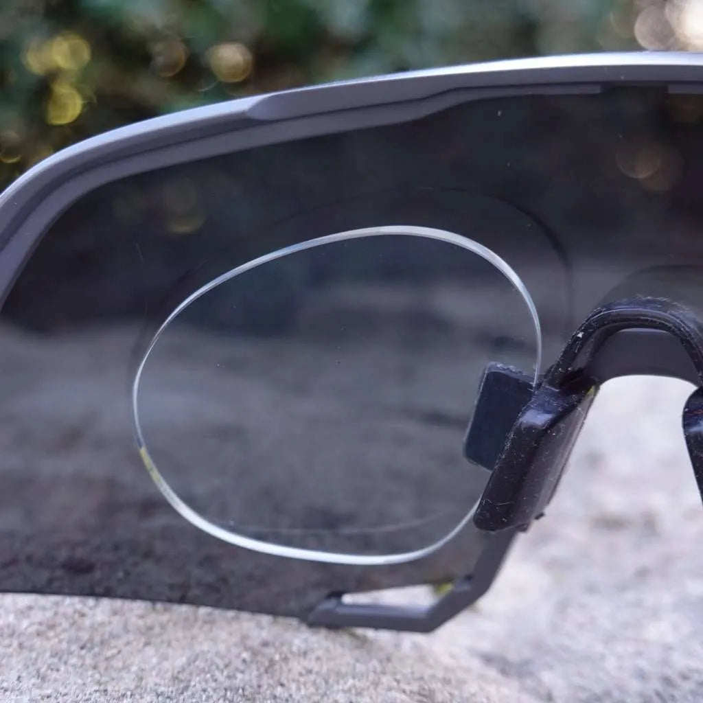 Rear close-up of sport sunglasses showing prescription lens in insert clip on granite surface